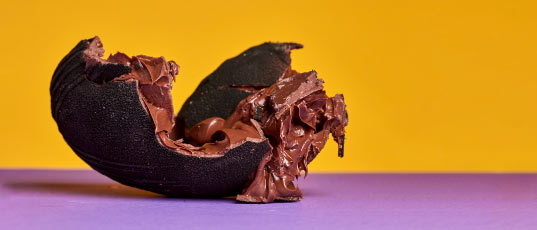 Huevo de pascua de Hedonist relleno de nutella sobre una mesa violeta con un fondo amarillo